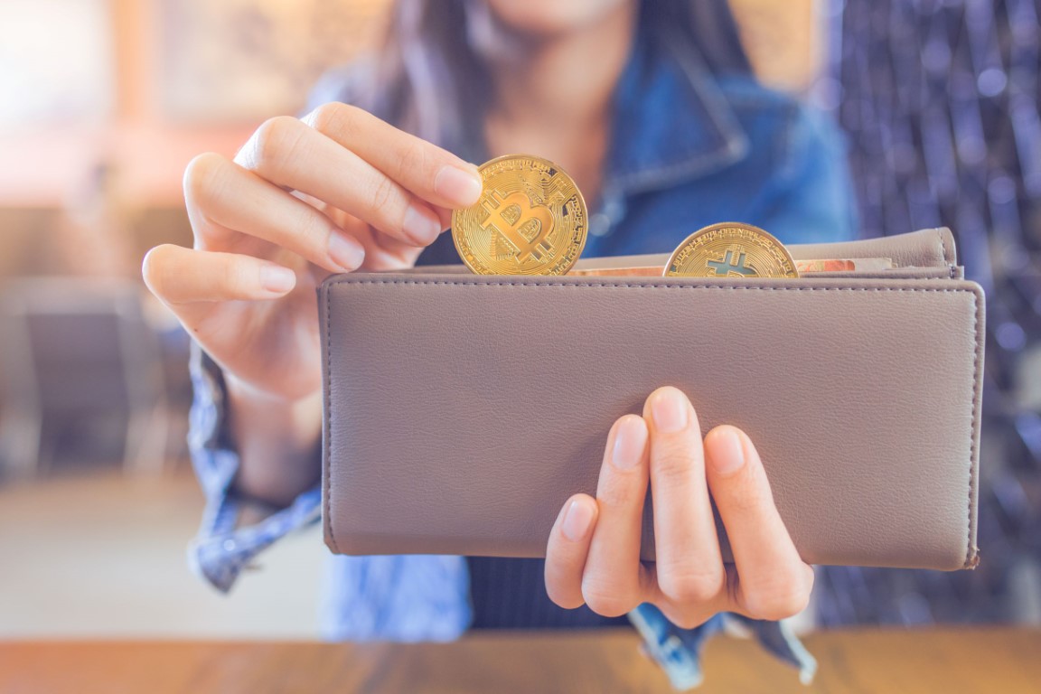 Woman hand is pulling a bitcoin out of a wallet 