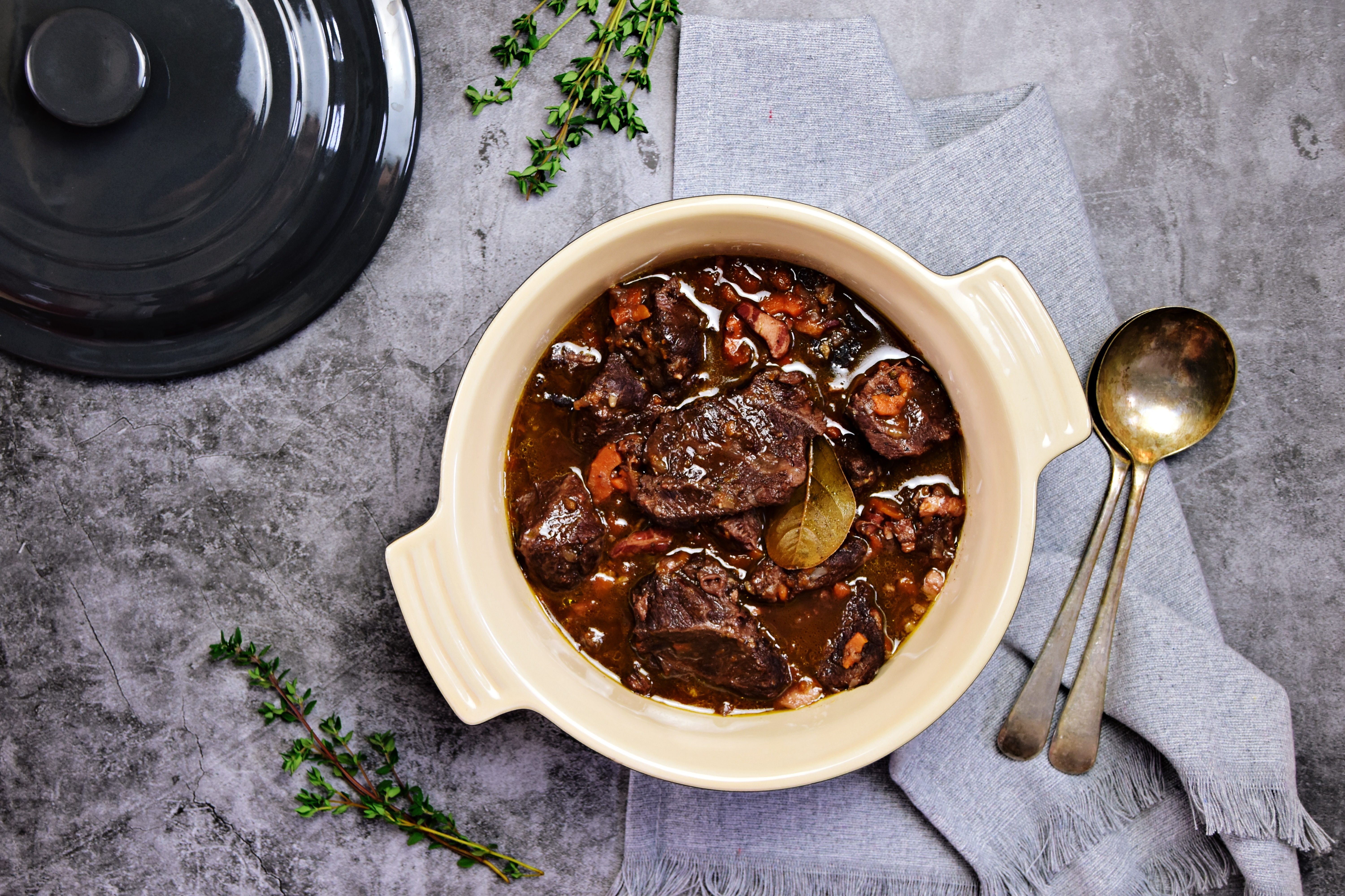 Beef bourguignon in the pot on the grey background, top view